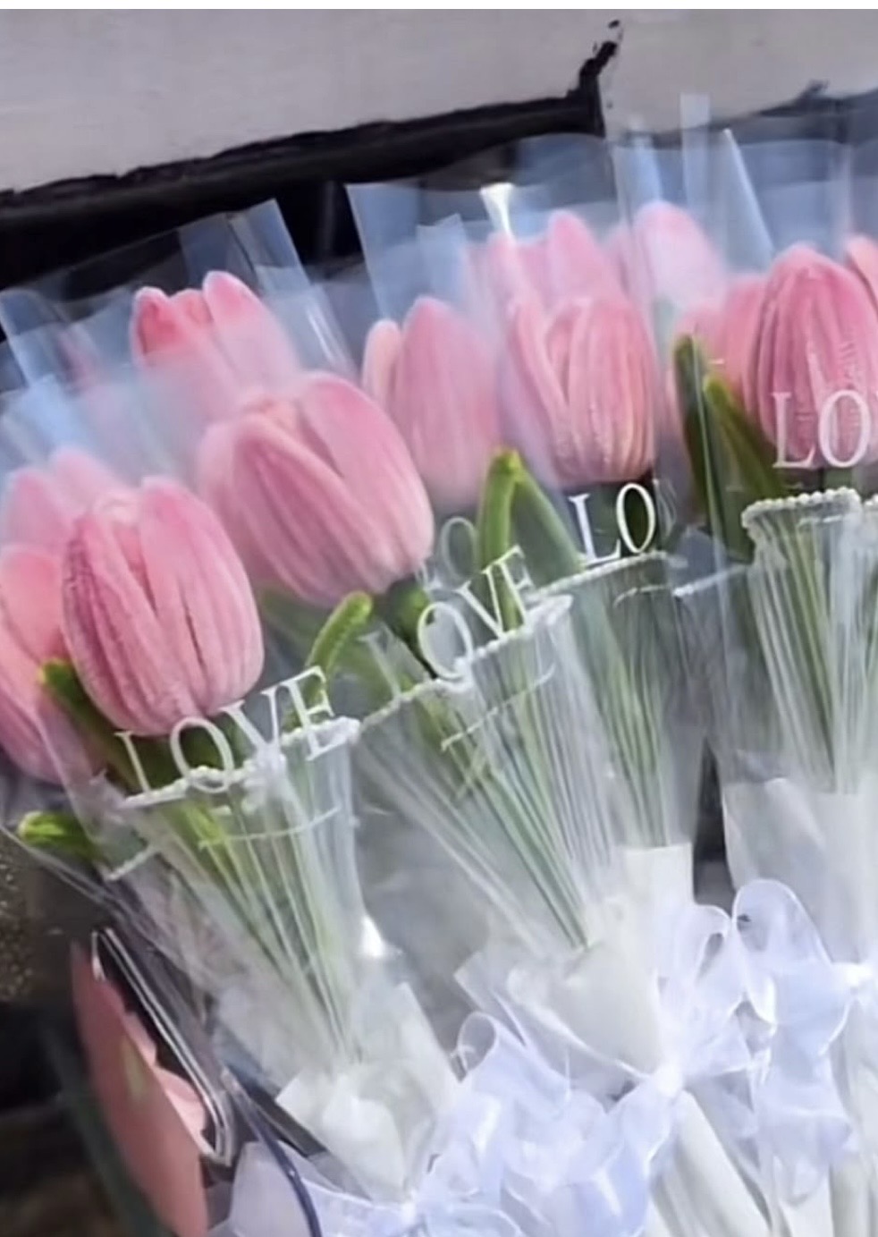 Pink pipe cleaner tulip bouquets in clear wrap with LOVE ribbon — elegant party favor